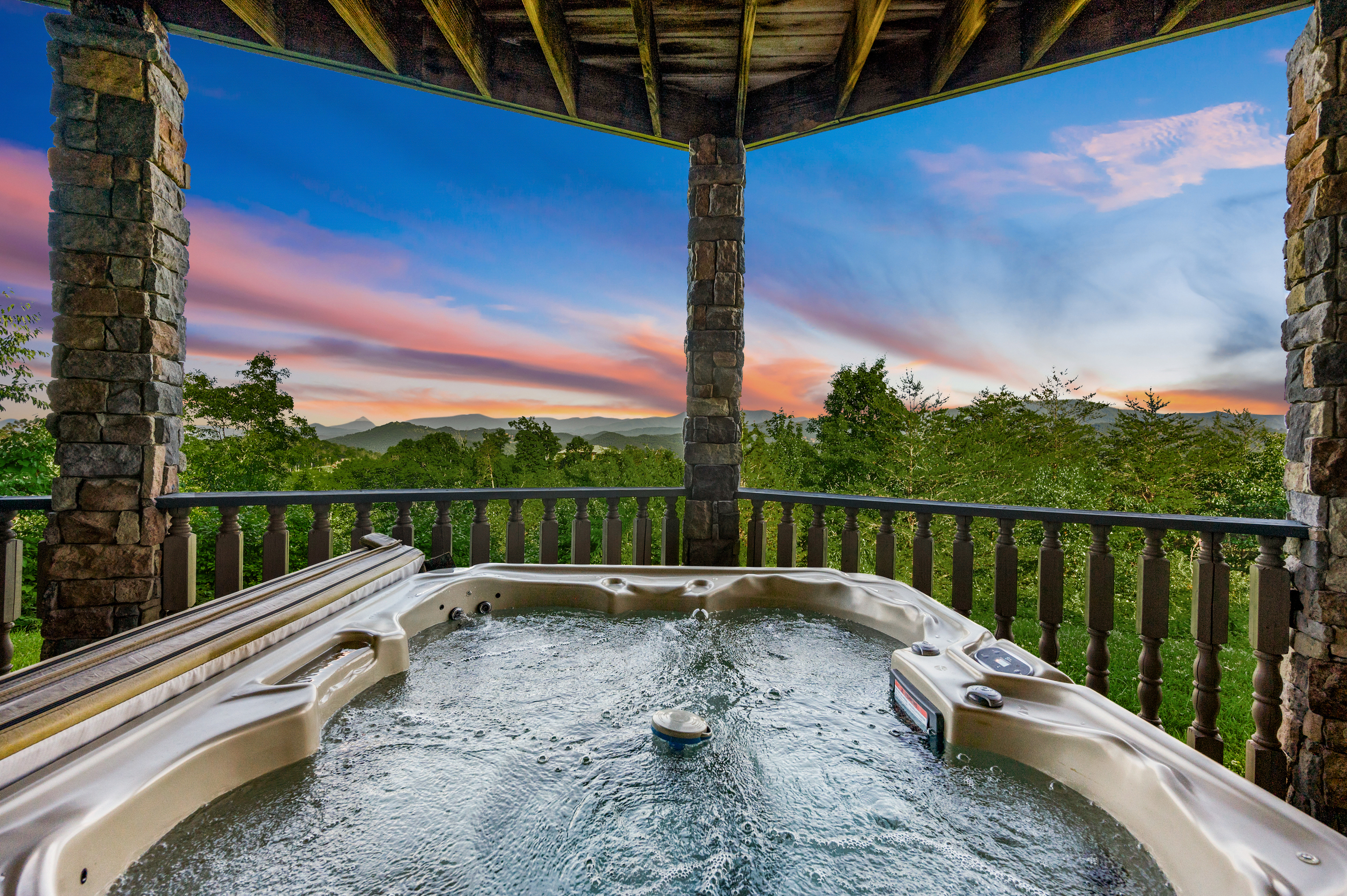 Bubbling hot tub on the covered deck overlooking the mountains at sunset