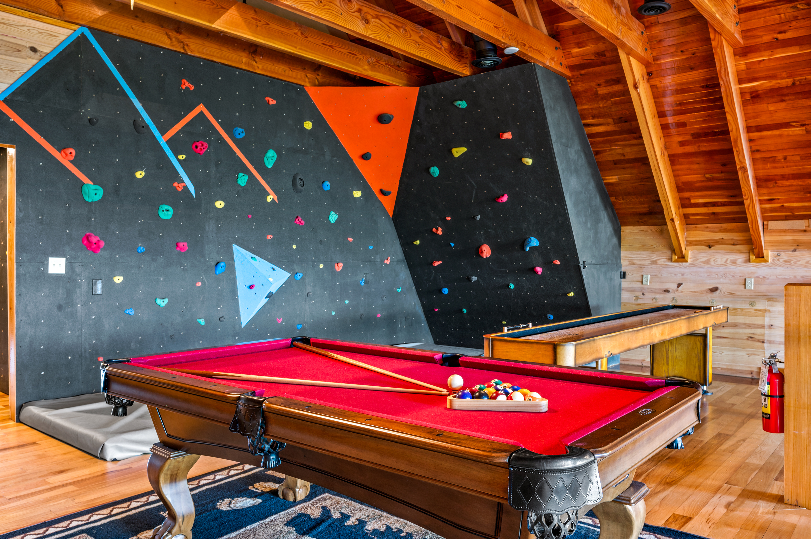 Indoor rock climbing wall, pool table, and shuffleboard at Majestica Lodge